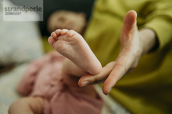 Hand of mother touching newborn daughter's foot