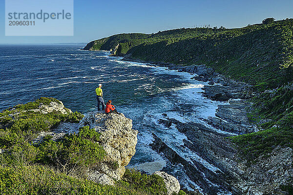 Hikers sitting on cliff and looking at Indian Ocean in Eastern Cape  South Africa