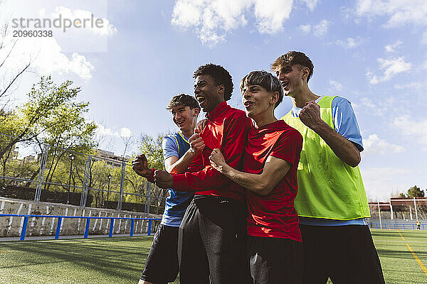 Happy soccer players cheering together on field