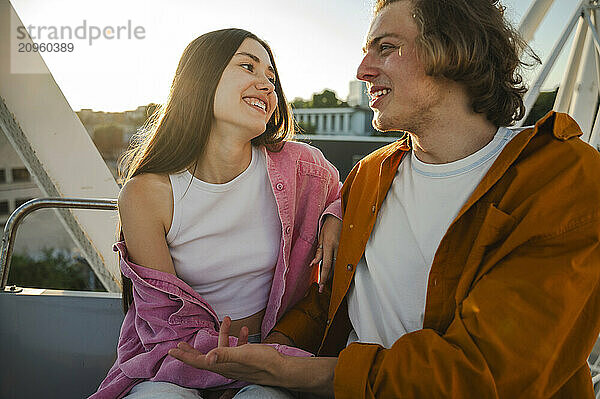 Happy couple sitting on ferris wheel in amusement park