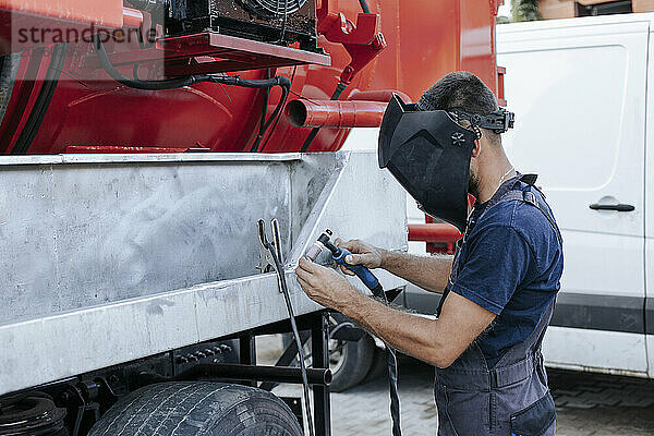 Mechanic is focused on vehicle repair outside garage