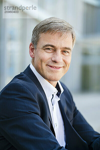 Portrait of a smiling businessman in front of office building