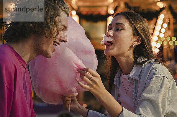 Happy couple eating cotton candy and having fun in amusement park