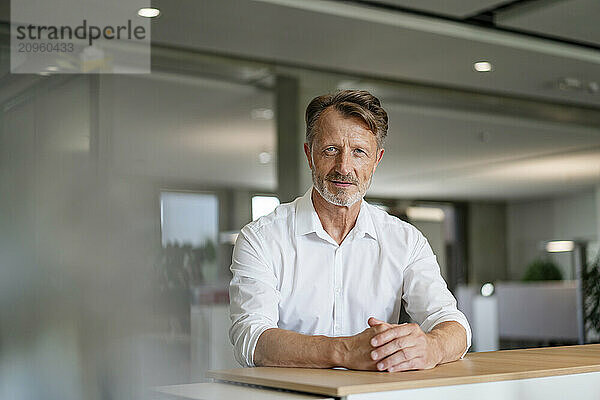 Elderly businessman leaning on table at office