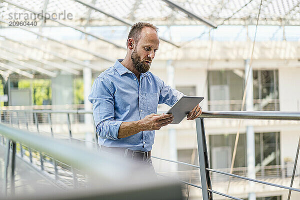 Experienced businessman using digital tablet standing in office building