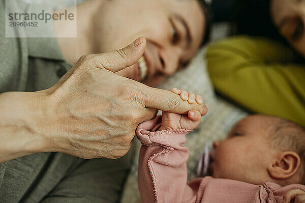 Newborn baby holding father's finger