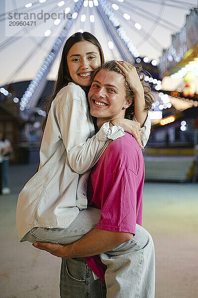 Happy girlfriend embracing boyfriend at amusement park