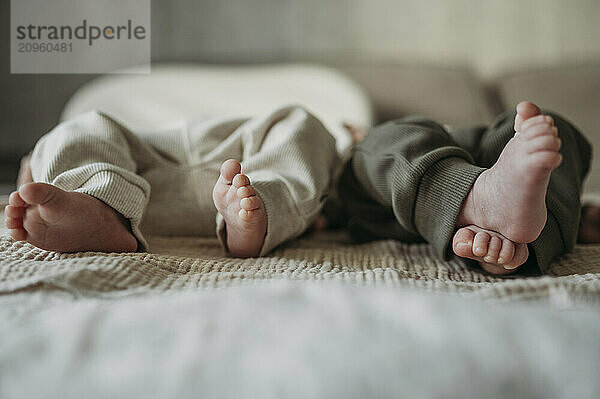 Feet of newborn twins lying on bed at home