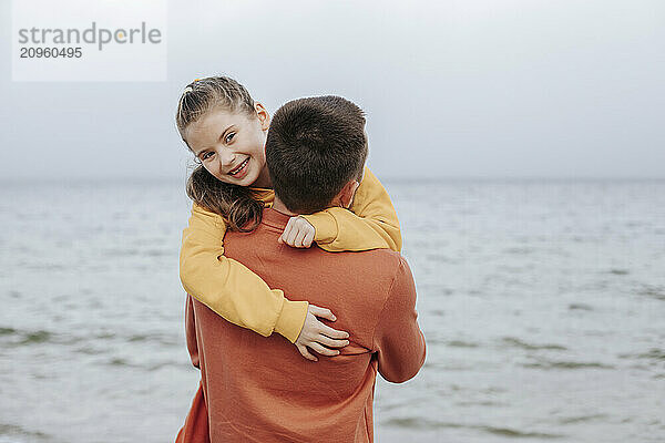 Father carrying daughter in arms at beach