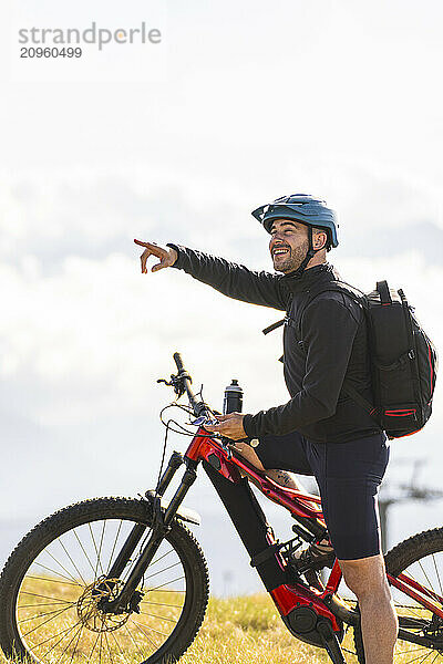 Smiling cyclist pointing direction on mountain