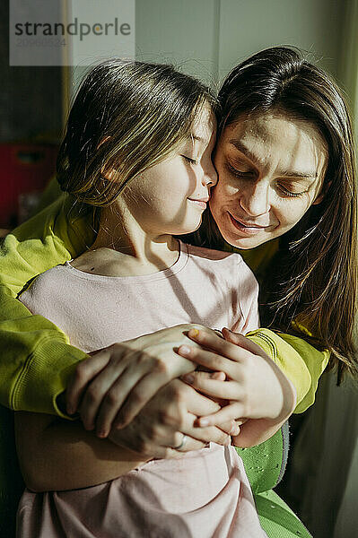 Smiling woman embracing daughter at home