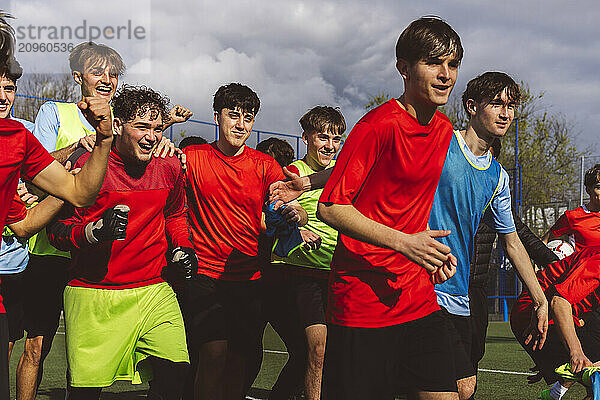 Happy soccer players winning match under sky at field