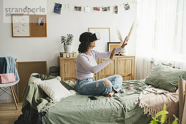 Girl gesturing with virtual reality simulators on bed at home