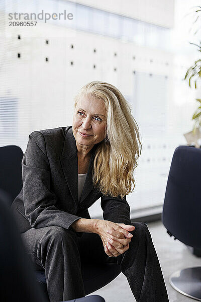 Senior businesswoman with long hair sitting on chair at office