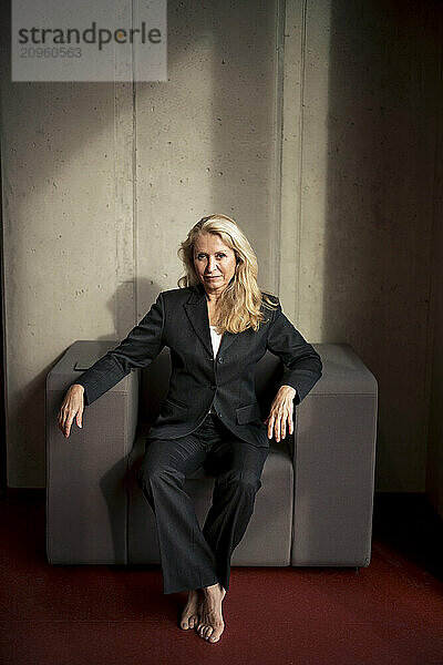 Blond senior businesswoman sitting on chair at office