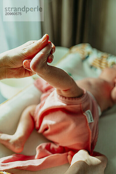 Mother holding newborn daughter's foot at home