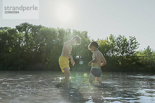 Brothers enjoying in river on sunny day