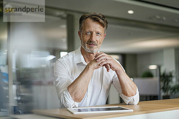 Senior businessman with hands clasped at office