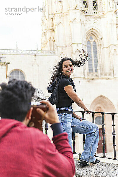 Man taking photo of girlfriend standing near railing