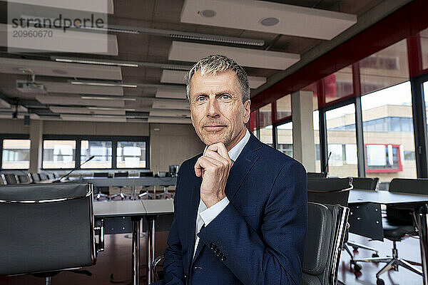 Senior businessman with hand on chin sitting at office