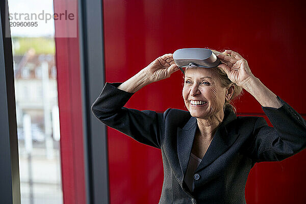 Happy businesswoman holding virtual reality headset at work place