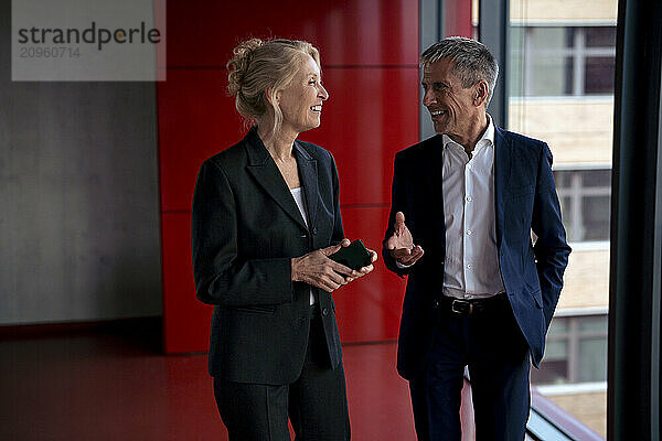 Smiling businessman gesturing and discussing with colleague at office