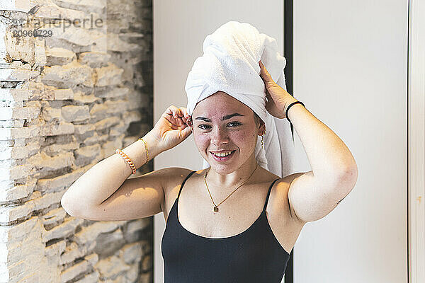 Smiling woman wearing towel standing at home