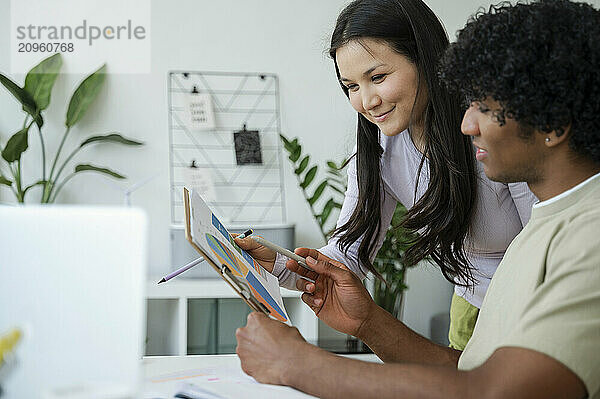 Young man explaining data to friend at home