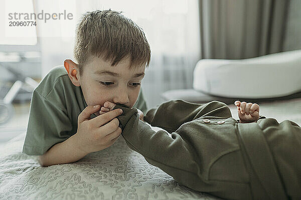 Boy kissing feet of baby brother at home