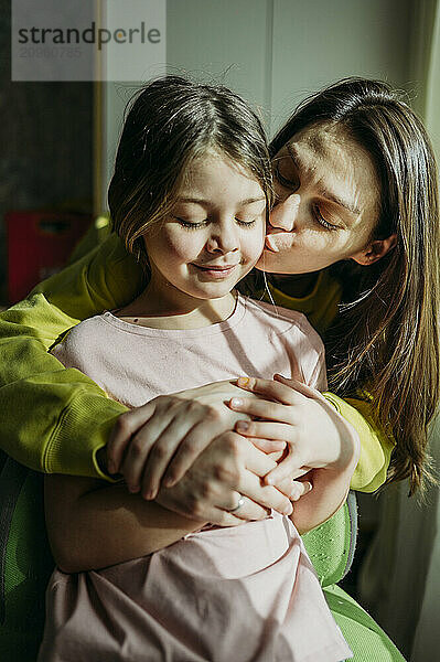 Mother kissing daughter at home