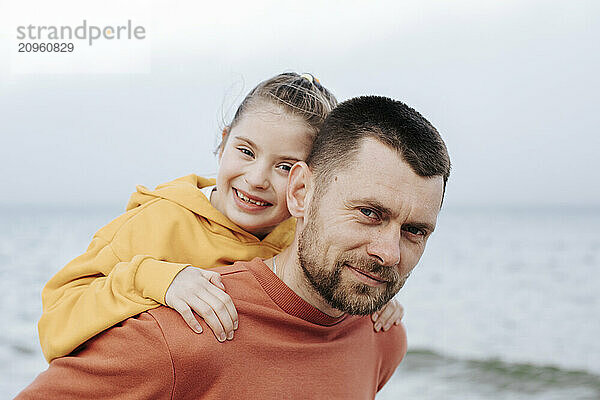 Father giving piggy back ride to daughter at beach