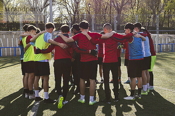 Soccer team huddling on sunny day