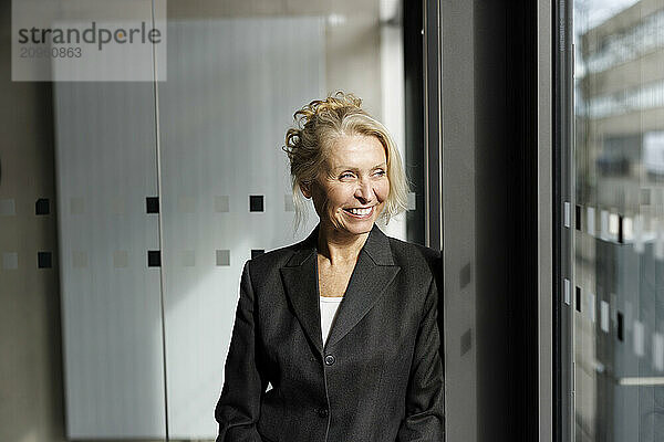 Happy businesswoman looking out of window at office