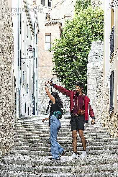 Man dancing with girlfriend on steps at street