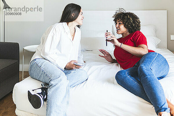 Woman showing smart phone to friend in hotel room