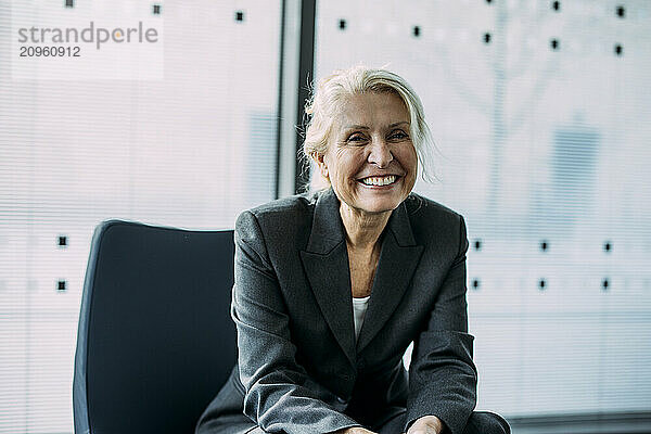 Happy senior businesswoman sitting on chair at office