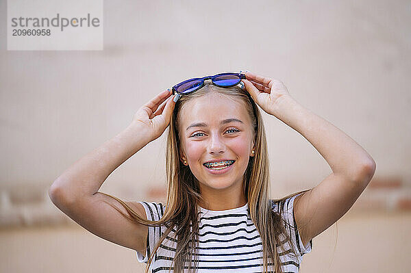 Blond hair girl with braces holding sunglasses