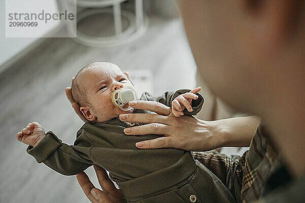 Newborn baby boy with pacifier at home