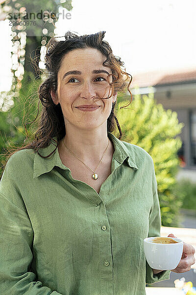 Smiling woman in green shirt holding coffee cup