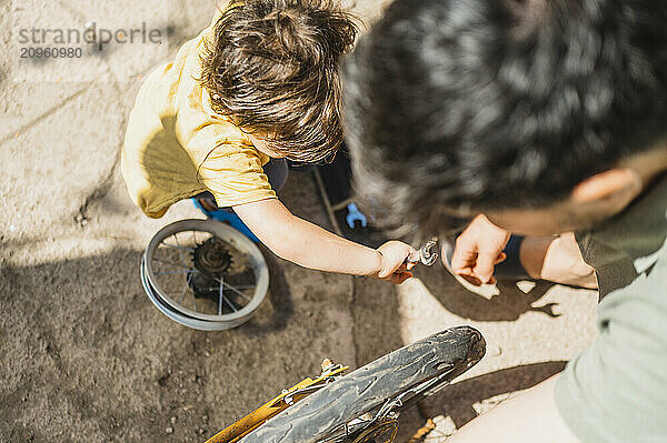 Father and son repairing old bicycle in back yard