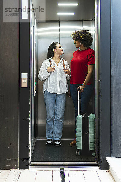 Tourist friends looking at each other in hotel elevator