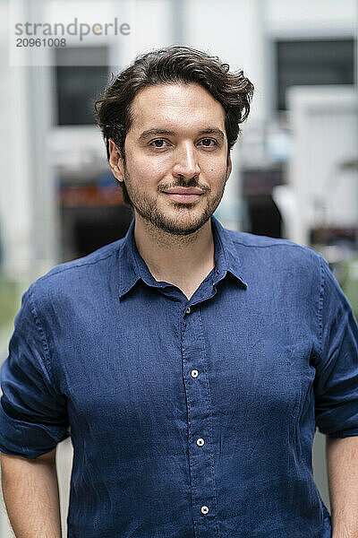 Confident businessman in blue shirt at factory