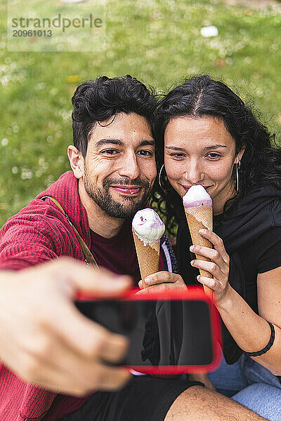 Beautiful couple taking selfie and eating ice cream in city