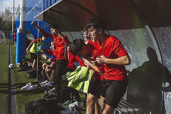 Cheerful soccer players cheering on sunny day