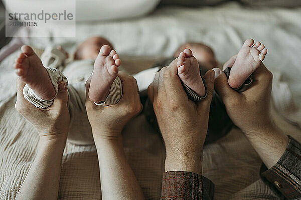 Parents holding baby boys legs at home