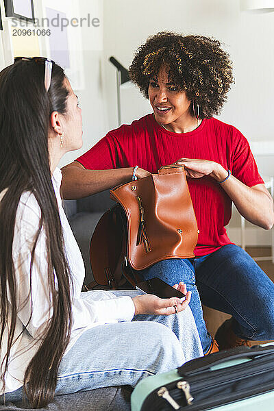 Curly haired woman talking with friend in hotel room