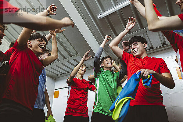 Cheerful soccer players dancing in locker room