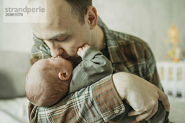 Affectionate father kissing son at home