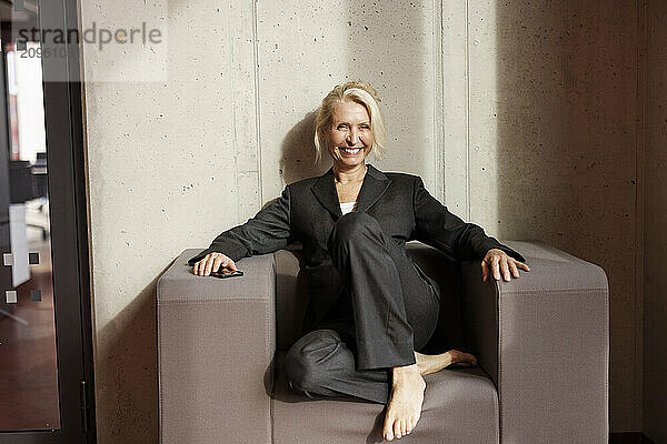 Smiling businesswoman sitting on chair at office