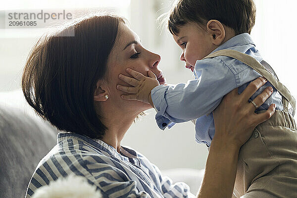 Mother holding and embracing baby boy at home